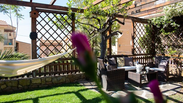 Eine Terrasse mit Korbmöbeln, einer Hängematte und einer Holzpergola.