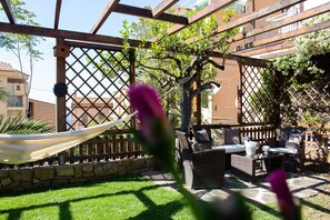Eine Terrasse mit Korbmöbeln, einer Hängematte und einer Holzpergola.