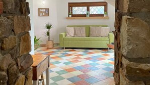 Ein gemütliches Zimmer mit einem grünen Sofa, einem Holztisch und einem farbenfrohen Schachfußboden.