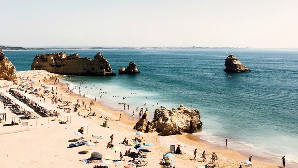 A beach with rocky formations, clear blue water, and a sandy shore with umbrellas and people. - Beautiful Spacious Villa in 2,5 Acres A/C Heated Pool Nr Golf & Beaches Sleeps 8 (Budens near VILA DO BISPO)