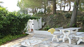 A patio with stone flooring, white benches, and a white wall with a window. - Beautiful Spacious Villa in 2,5 Acres A/C Heated Pool Nr Golf & Beaches Sleeps 8 (Budens near VILA DO BISPO)