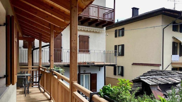 Ein Holzbalkon mit Blick auf angrenzende Gebäude und einen kleinen Garten.