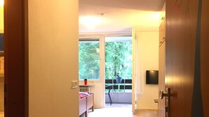 A hallway leading to a room with a view of trees through a window.