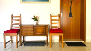 A wooden desk with two chairs, a potted plant, and a painting of birds on the wall.