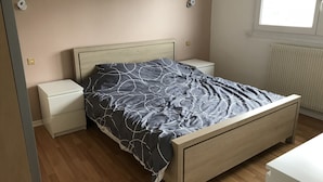 A bedroom with a bed, nightstands, a radiator, and a window. - Leffrinckoucke Plage (Leffrinckoucke)