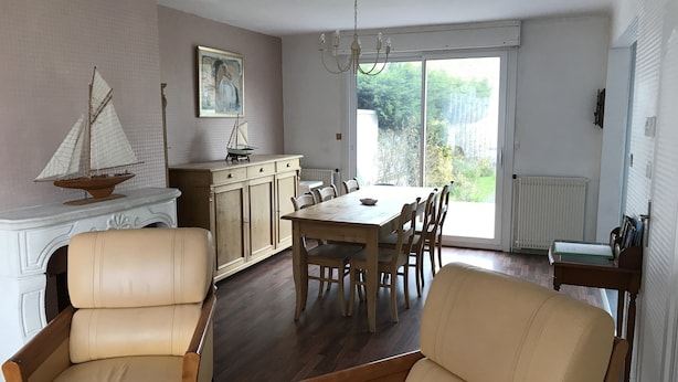 A dining area with a wooden table and chairs, a fireplace with a sailboat decoration, and a view through a large window. - Leffrinckoucke Plage (Leffrinckoucke)