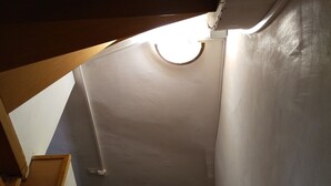 Eine Holztreppe mit einer weißen Wand und einer runden Leuchte am oberen Ende.