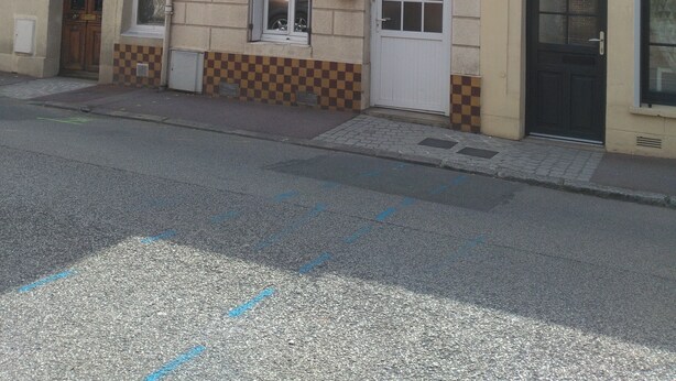 Ein zweistöckiges Gebäude mit nummerierten Türen, einem sichtbaren Fenster und einem Schachbrettmuster im unteren Bereich.