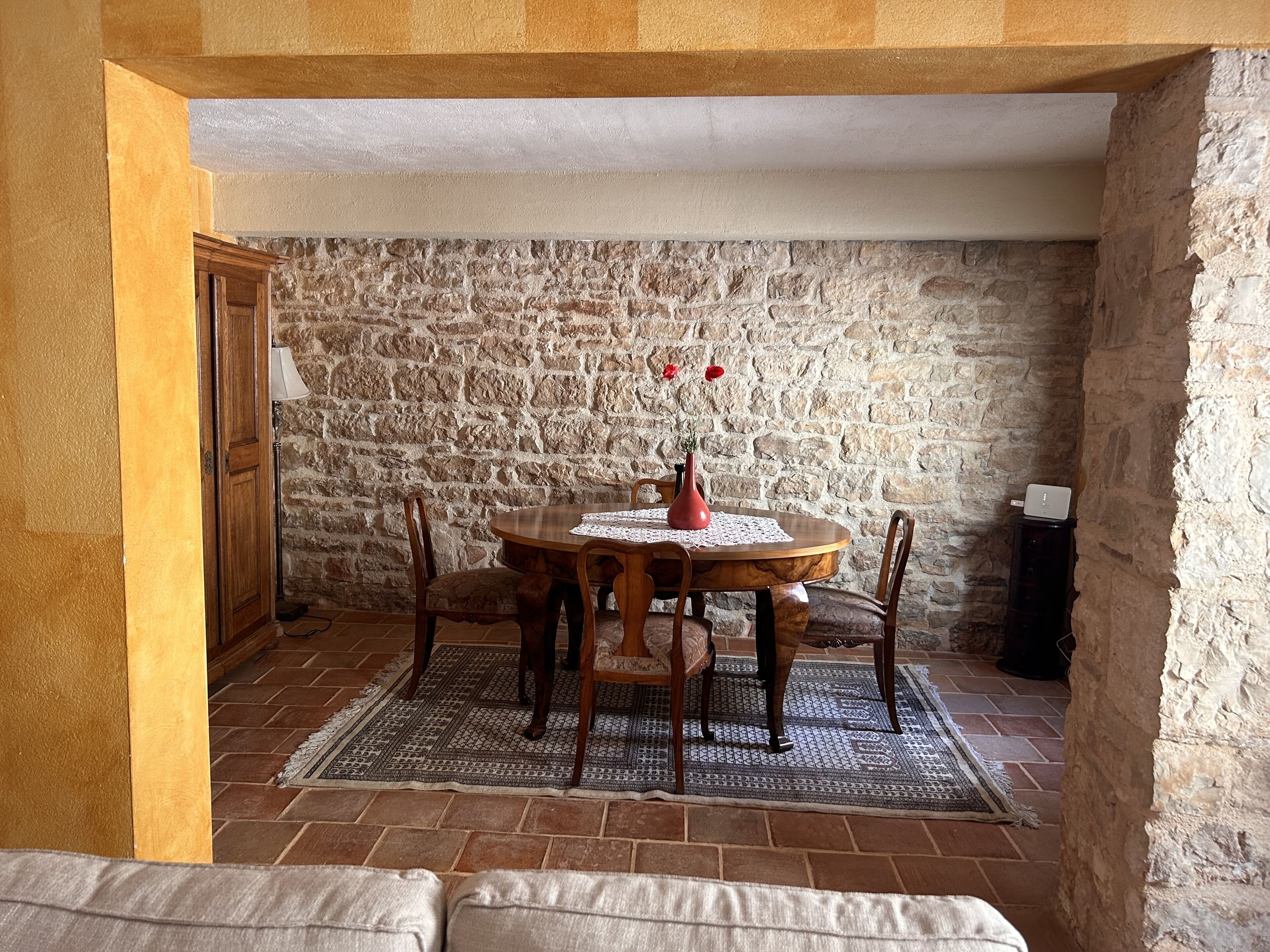 A dining area with a stone wall, wooden table, and chairs.