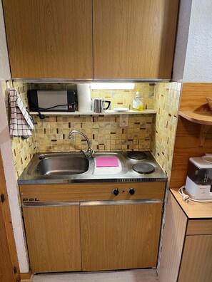 A compact kitchen with a sink, stove, and microwave.