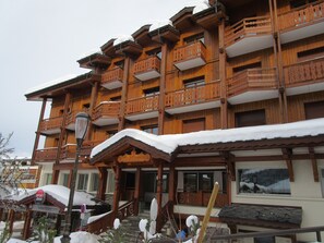 A multi-story wooden building with balconies and a covered entrance.