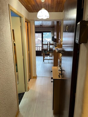 A narrow hallway with a wooden ceiling and a ceiling light fixture.