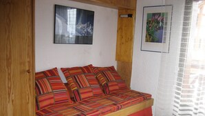 A cozy room with a wooden bed, a framed picture on the wall, and a window with a white curtain.