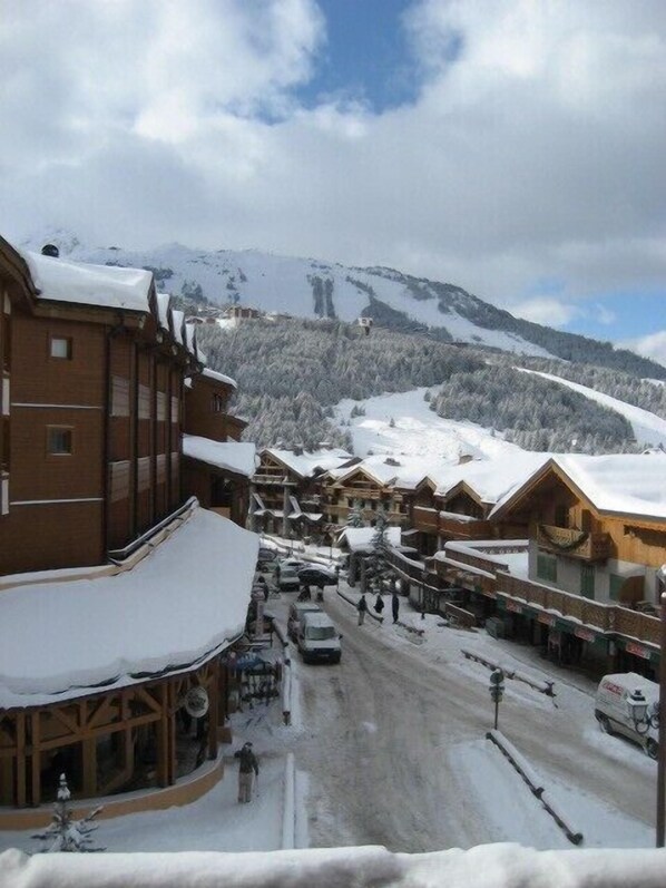 A snow-covered mountain town with wooden buildings, a main street, and a view of a snow-covered mountain.
