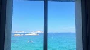 A view from a room with a large window overlooking a coastal area with clear blue water and rocky outcrops. - Seafront Cabanon, Access Private to the Sea, Corniche Malmousque! (Marseille)