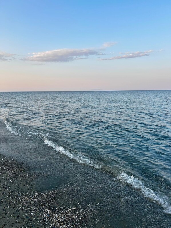 Una playa con cielo despejado y mar tranquilo.
