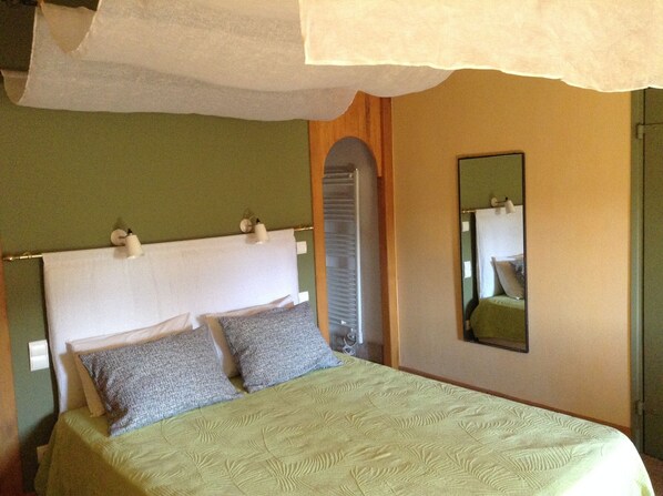 A bed with a white headboard, two pillows, and a green bedspread.