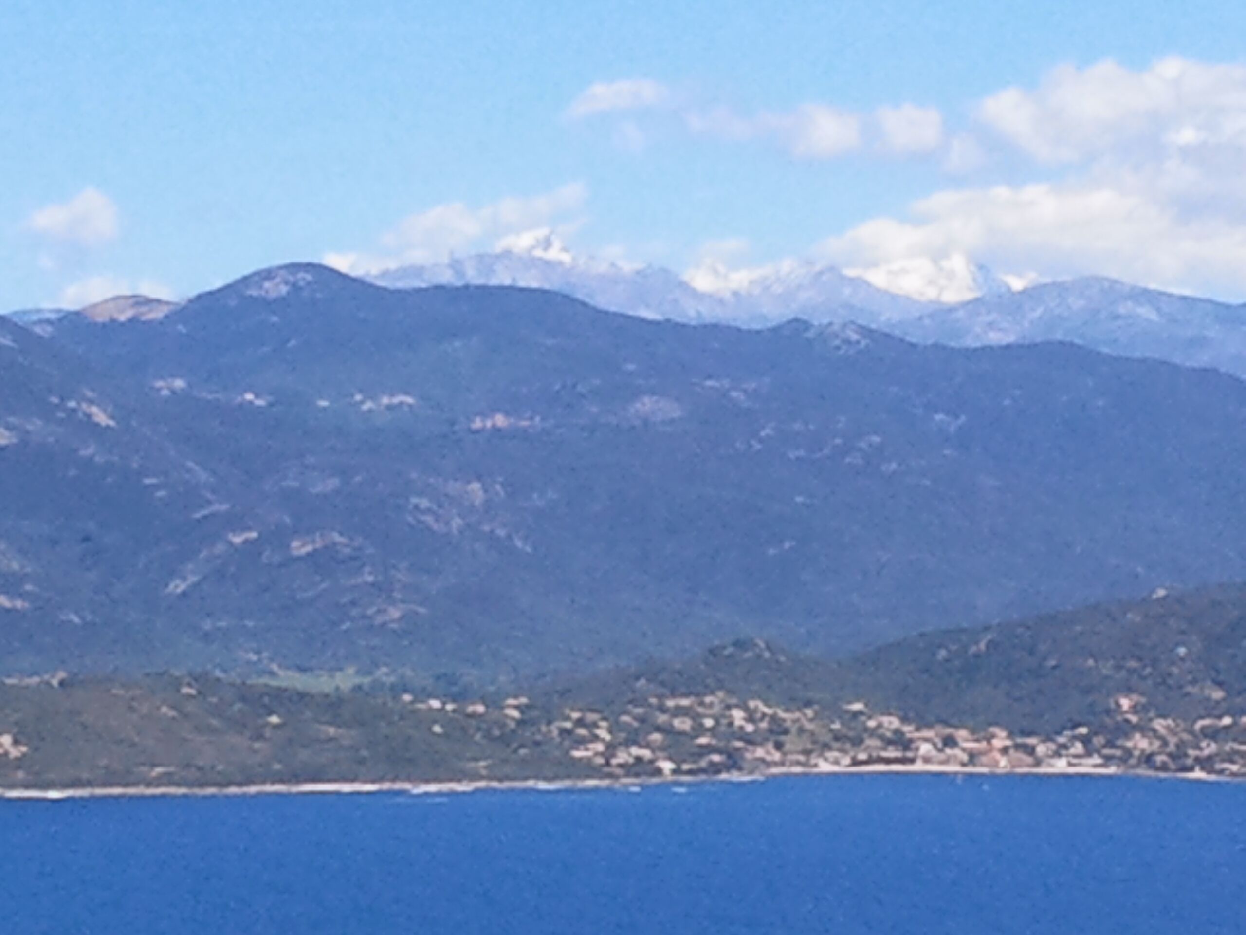 A coastal town with a mountain range in the background.