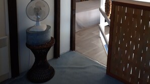 Une pièce avec un plafond en bois, un lit, une lampe fixée au mur et un tableau encadré.