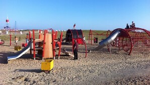 Un parque infantil en la playa con toboganes y estructuras para escalar.