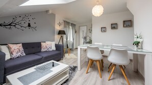 A modern living room with a sofa, coffee table, dining table, and chairs.