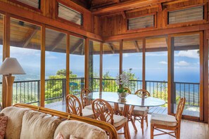 A wooden deck with a glass table and chairs, overlooking a scenic landscape. - Relax and Enjoy! Five Star Accommodations at Affordable Rates! (Captain Cook)