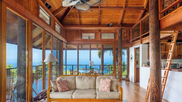 Un intérieur en bois avec un canapé, une table et une vue sur l’océan.
