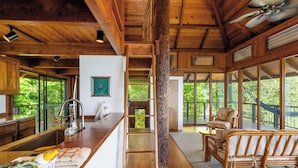 Un intérieur en bois avec un comptoir de cuisine, une échelle, un canapé et de grandes fenêtres.