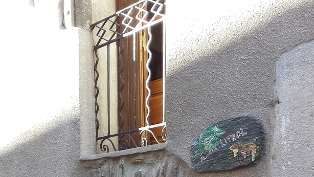 Fachada de piedra con puerta de madera y barandilla de balcón metálica.