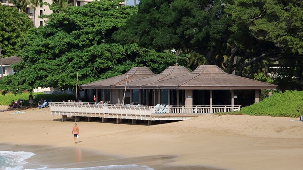 A beach with a covered pavilion, sandy beach, and trees in the background. - Maui Eldorado Beachfront Resort - Apt I-101 - Two Bedroom Vacation Rental Condo (Lahaina)