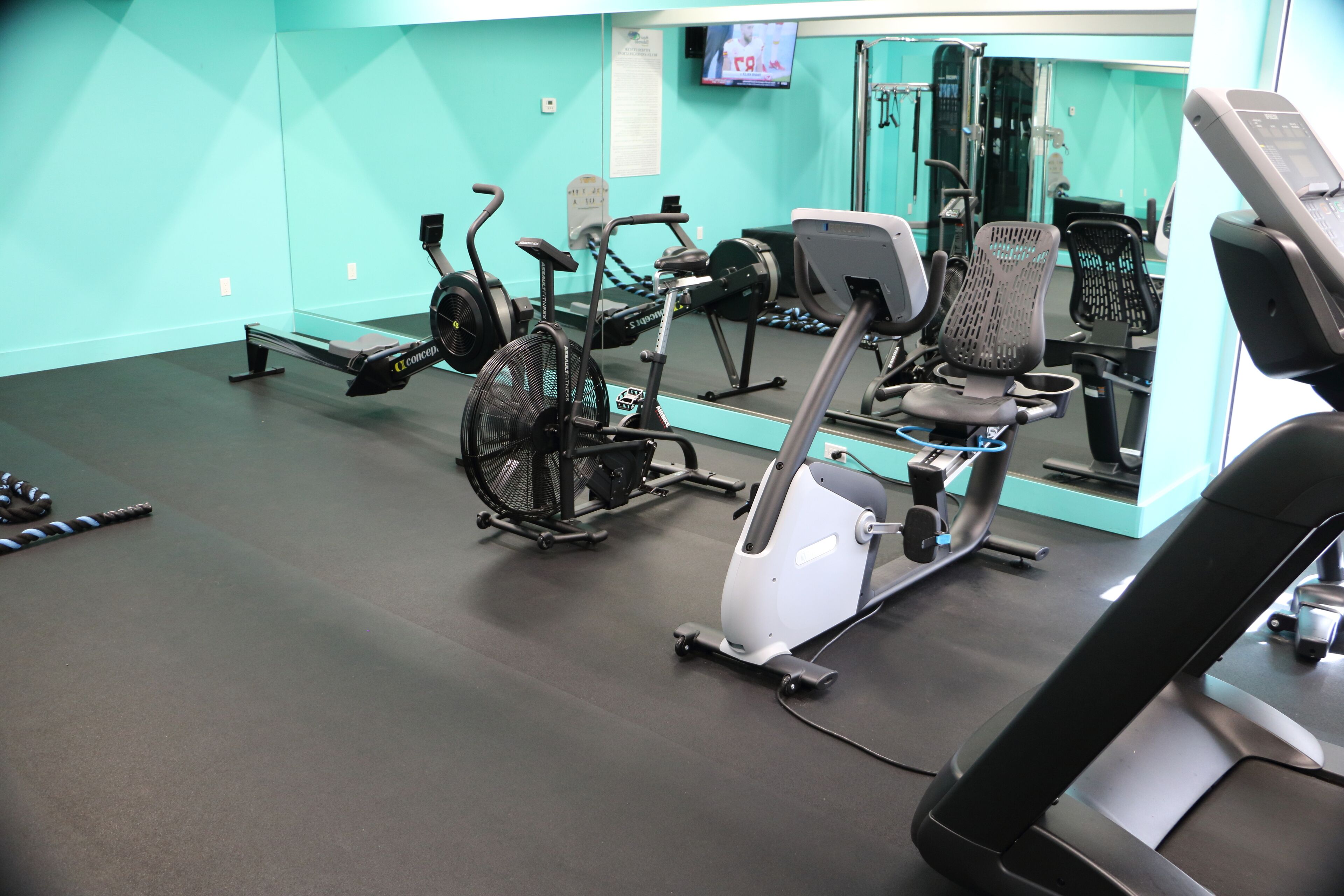 Une salle de sport équipée de divers appareils d’exercice, notamment des vélos d’appartement et des tapis de course.