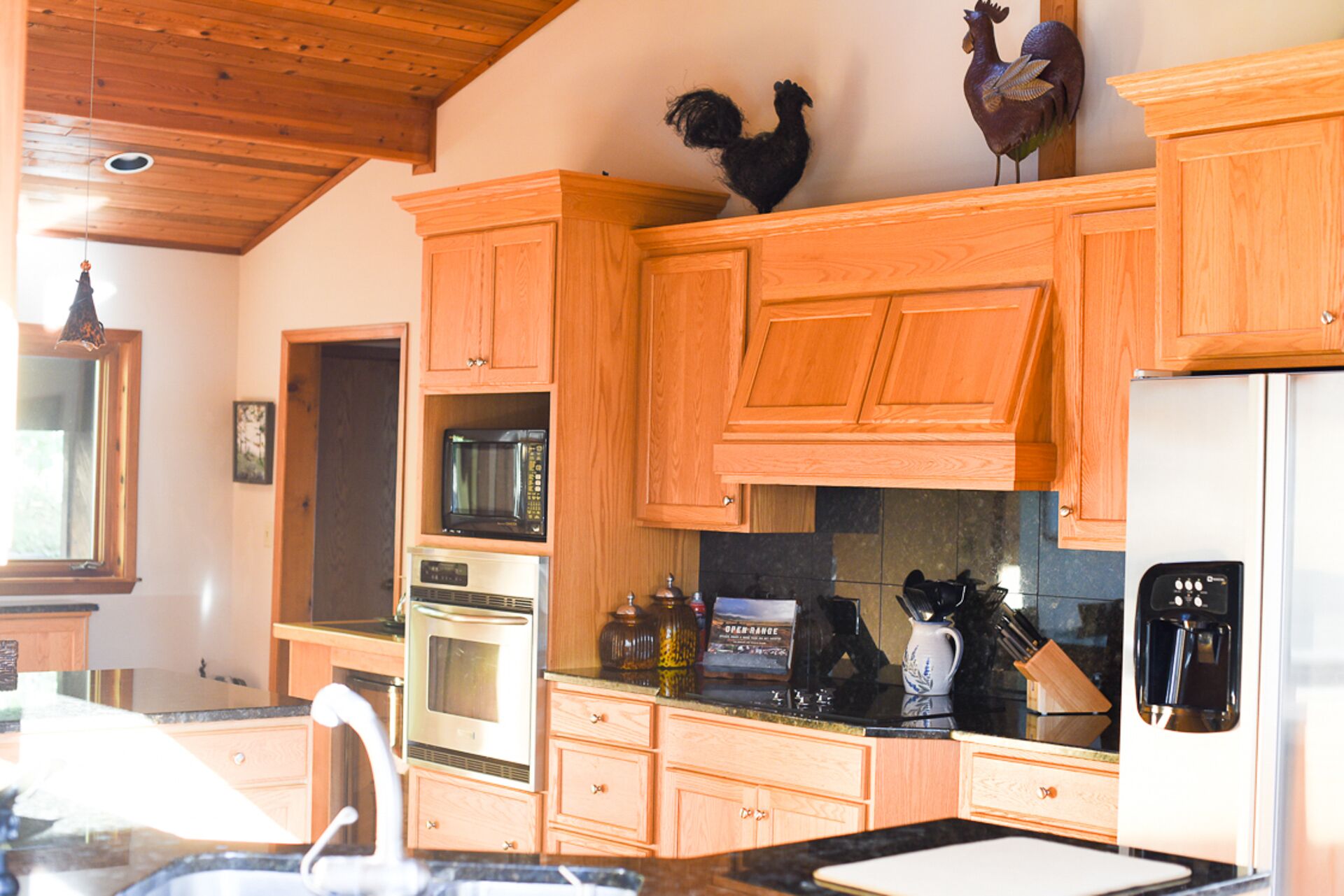 A kitchen with wooden cabinets, a microwave, an oven, a coffee maker, and a refrigerator.