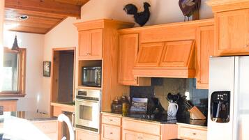 A kitchen with wooden cabinets, a microwave, an oven, a coffee maker, and a refrigerator.