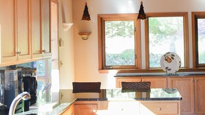A kitchen with wooden cabinets, a granite countertop, a sink, and pendant lights.