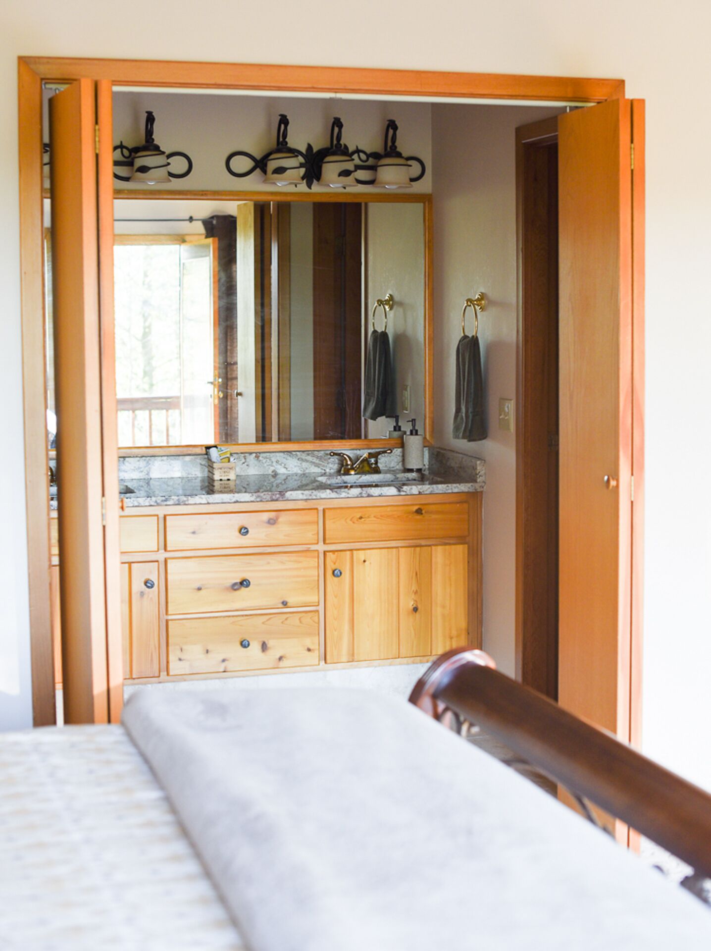 Een slaapkamer met een houten opbergmeubel, een grote spiegel en een bed met hoofdeinde.