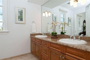 A bathroom with two sinks, wooden cabinets, a large mirror, and a potted orchid. - Villa Vivace - New Luxurious Seaside Home (Providenciales)