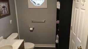 A bathroom with a toilet, sink, towel rack, and a window. - Cozy 2BR Retreat Near Hurley-Ironwood – Trails, Skiing, Snomobiling (Montreal)