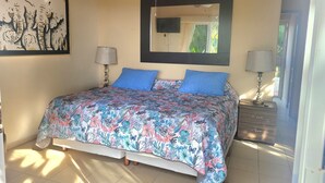 A bedroom with a floral bedspread, a large mirror, and two bedside lamps. - Secluded 2 bedroom duplex with private pool and gorgeous jungle and ocean views! (El Divisadero)