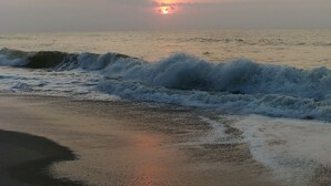 Une scène de plage avec des vagues et un coucher de soleil.
