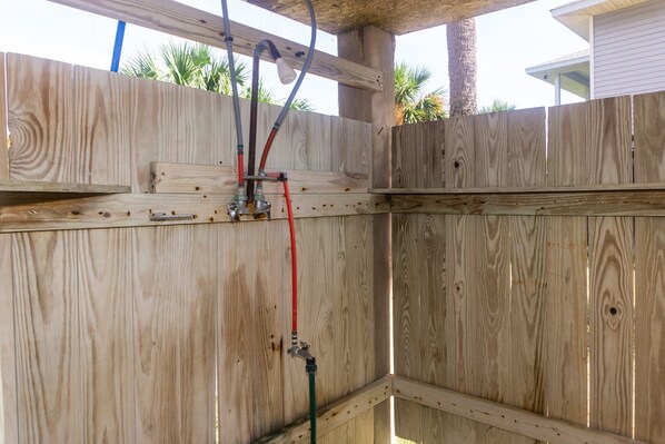 Une clôture en bois avec des tuyaux de plomberie apparents et un support métallique.