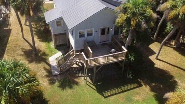 A beachfront property with a covered patio, a small deck, and a view of the ocean. - The Gulls Nest Beach House (Edisto Island)