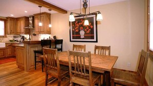 A wooden dining table with chairs, a kitchen with wooden cabinets, and a chandelier. - Red Poppy- Beautiful home 3 blocks from Elk Ave (Crested Butte)