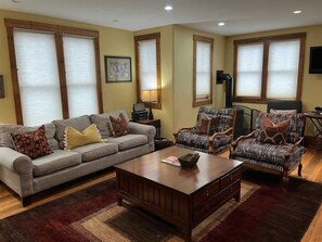 A living room with a sofa, armchairs, a coffee table, and a lamp.