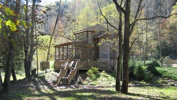 A cabin with a wooden deck and stairs leading up to it, surrounded by trees. - Peaceful Real Log Cabin Rushing Trout Stream  Jacuzzi Hot Tub (deep gap)