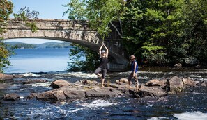 A stone bridge over a river with trees and a person performing a yoga pose. - Perfect Readaway Vacation Spot (Tupper Lake)