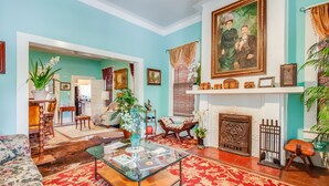 Uma sala de estar espaçosa com uma mesa de centro de vidro, uma lareira e um grande retrato na parede.