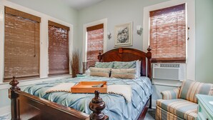 Quarto com cama de madeira, mesa de cabeceira, cadeira e cômoda.