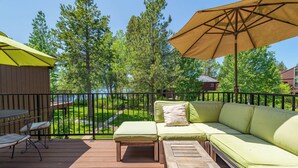 A wooden deck with a green sofa, a table, and an umbrella.