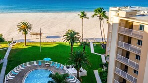 A pool area with a circular pool, lounge chairs, and palm trees. - Prime Beachfront with Views Views Views! (Siesta Key)