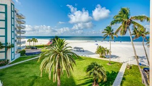 A beachfront hotel with a view of the ocean, palm trees, and a flag. - Prime Beachfront with Views Views Views! (Siesta Key)